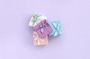 Pile of a small colored gift boxes with ribbons lies on a violet background. Minimalism flat lay top view photo