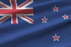 New Zealand flag with big folds waving close up under the studio light indoors. The official symbols and colors in banner photo