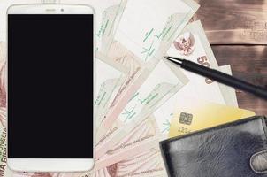 5000 Indonesian rupiah bills and smartphone with purse and credit card. E-payments or e-commerce concept. Online shopping and business with portable devices photo