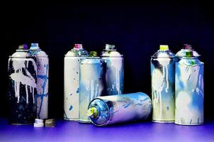 Still life with a large number of used colorful spray cans of aerosol paint lying on the treated wooden surface in the artist's graffiti workshop. Dirty and stained cans for spray art photo