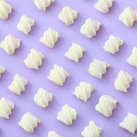 Colorful marshmallow laid out on violet paper background. pastel creative textured pattern. minimal photo