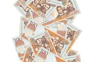 Billetes de 100 pesos dominicanos volando aislados en blanco. muchos billetes cayendo con copyspace blanco en el lado izquierdo y derecho foto