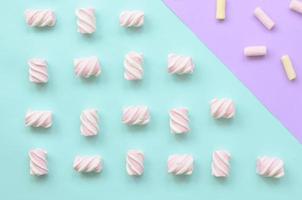 Colorful marshmallow laid out on violet and blue paper background. pastel creative textured pattern. minimal photo