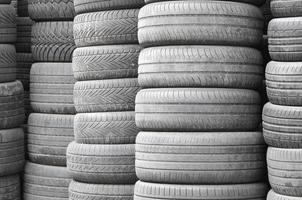 Old used tires stacked with high piles in secondary car parts shop garage photo