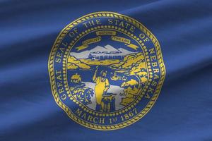 Nebraska US state flag with big folds waving close up under the studio light indoors. The official symbols and colors in banner photo