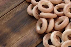 A lot of fresh yellow bagels lie on the surface of the old dark wood. A popular kind of flour products. One of the traditional Russian treats for tea photo