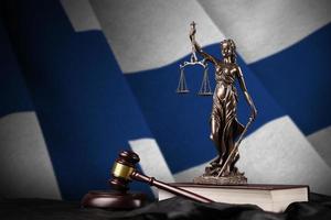 Finland flag with statue of lady justice, constitution and judge hammer on black drapery. Concept of judgement and guilt photo