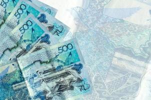 500 Kazakhstani tenge bills lies in stack on background of big semi-transparent banknote. Abstract business background photo