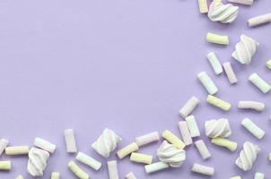 Colorful marshmallow laid out on violet paper background. pastel creative textured framework. minimal photo