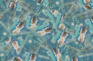 5 Canadian dollars bills lies in big pile. Rich life conceptual background photo