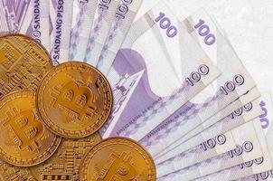100 Philippine piso bills and golden bitcoins. Cryptocurrency investment concept. Crypto mining or trading photo
