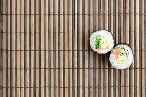 Sushi rolls lies on a bamboo straw serwing mat. Traditional Asian food. Top view. Flat lay minimalism shot with copy space photo