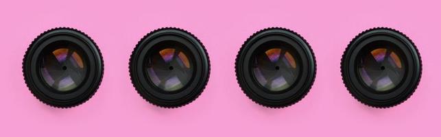 A few camera lenses with a closed aperture lie on texture background of fashion pastel pink color paper in minimal concept. Abstract trendy pattern photo