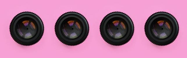 A few camera lenses with a closed aperture lie on texture background of fashion pastel pink color paper in minimal concept. Abstract trendy pattern photo