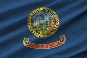 Idaho US state flag with big folds waving close up under the studio light indoors. The official symbols and colors in banner photo