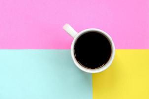 Small white coffee cup on texture background of fashion pastel blue, yellow and pink colors paper in minimal concept photo