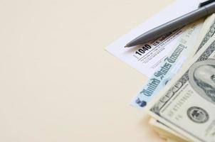 1040 Individual Income tax return form with Refund Check and hundred dollar bills on beige background photo