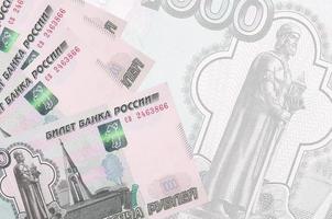 Los billetes de 1000 rublos rusos se encuentran apilados en el fondo de un gran billete semitransparente. fondo de negocios abstracto foto