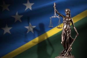 Solomon Islands flag with statue of lady justice and judicial scales in dark room. Concept of judgement and punishment photo