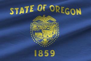 Oregon US state flag with big folds waving close up under the studio light indoors. The official symbols and colors in banner photo