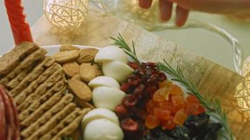 Flat charcuterie with salami, different kinds of cheese. It has dried fruits, various nuts and honey. Holiday arrangement with burning candles video