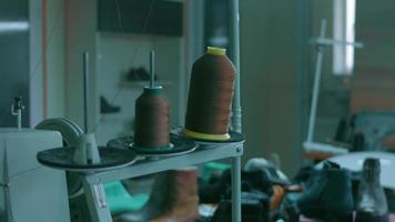 Spools of thread for sewing shoes in dark colors stand on a shelf video