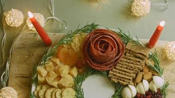 Flat charcuterie with salami, different kinds of cheese. It has dried fruits, various nuts and honey. Holiday arrangement with burning candles video