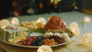 Charcuterie plate with salami, different kinds of cheese. It has dried fruits, various nuts and honey. Holiday arrangement with burning candles video