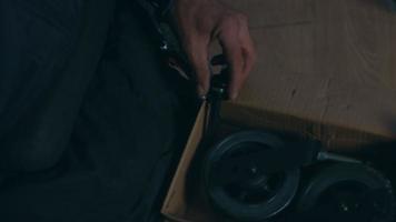 Side view of one American male workers in a workshop at a factory making wheelchairs, sitting at a workbench using hand tools and assembling parts of a product, sitting in wheelchairs video