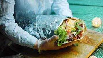 très gros burrito avec de la viande d'avocat et de chorizo. tournage dans un cadre romantique. prise de vue macro video