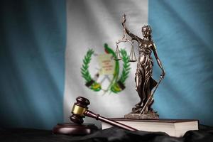 Guatemala flag with statue of lady justice, constitution and judge hammer on black drapery. Concept of judgement and guilt photo