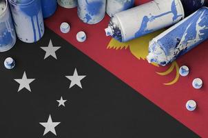Papua New Guinea flag and few used aerosol spray cans for graffiti painting. Street art culture concept photo