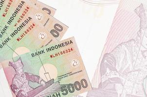 Los billetes de 5000 rupias indonesias se encuentran apilados en el fondo de un gran billete semitransparente. fondo de negocios abstracto foto