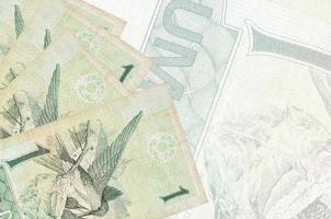 1 Brazilian real bills lies in stack on background of big semi-transparent banknote. Abstract business background photo