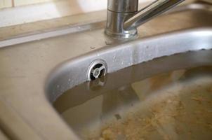 Stainless steel sink plug hole close up full of water and particles of food photo