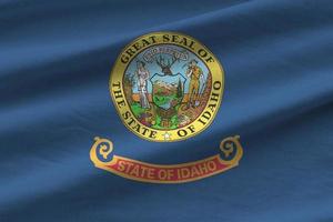 Idaho US state flag with big folds waving close up under the studio light indoors. The official symbols and colors in banner photo