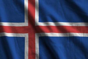 Iceland flag with big folds waving close up under the studio light indoors. The official symbols and colors in banner photo