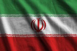 Iran flag with big folds waving close up under the studio light indoors. The official symbols and colors in banner photo