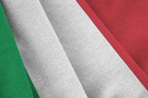 Italy flag with big folds waving close up under the studio light indoors. The official symbols and colors in banner photo