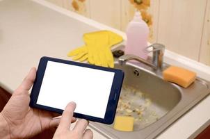 The landlord uses the tablet to call a cleaner in order to clean the clogged kitchen sink photo