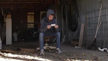 een jong Mens, tiener jongen zittend in garage op zoek Bij fotograaf video