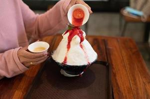 Korean shaved ice dessert with sweet toppings, Strawberry Bingsu on wood table photo