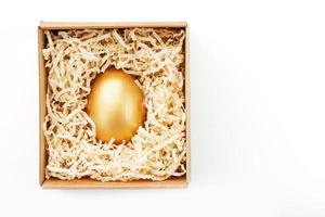Egg made of gold in a wooden box on a white background. The concept of exclusivity and superprize. Minimalistic composition. photo