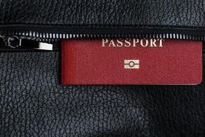 Passport looks out of the pocket of a black leather bag close-up, macro Handmade, natural materials. photo