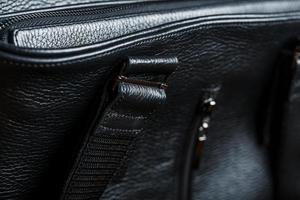 Black notebook peeking out of the pocket of a black leather bag close-up, macro Handmade, natural materials. photo