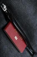 Passport looks out of the pocket of a black leather bag close-up, macro Handmade, natural materials. photo