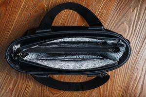 Black notebook peeking out of the pocket of a black leather bag close-up, macro Handmade, natural materials. photo