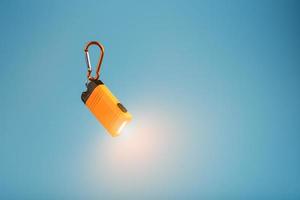 Orange led Flashlight with a carabiner on a blue background. LED lights in flight. photo