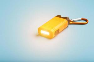 Orange led Flashlight with a carabiner on a blue background. LED lights in flight. photo