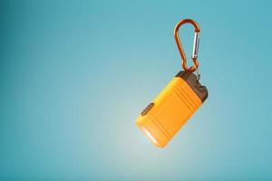 Orange led Flashlight with a carabiner on a blue background. LED lights in flight. photo